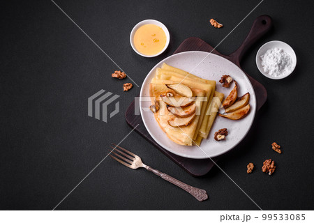 Delicious fresh baked pancakes with honey and fruits on a concrete background Delicious fresh baked pancakes with honey and fruits on a concrete background 99533085