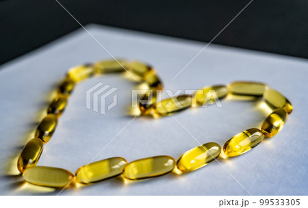 Yellow clear omega-3 gel capsules in the shape of a heart Yellow clear omega-3 gel capsules in the shape of a heart 99533305