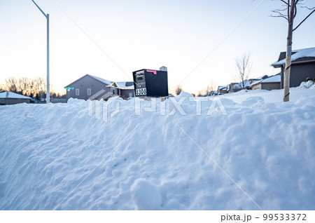 Residential mailbox blocked by a snow pile left by a plow after clearing a street. 99533372