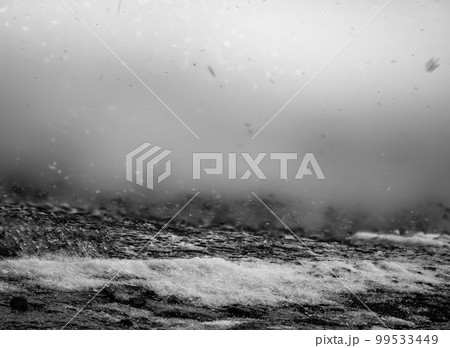 Blowing snow and Focus stacked ground level view of ice accumulation on a sidewalk with blowing snow.  99533449