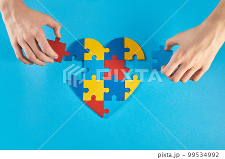 Autistic boy hands holding jigsaw puzzle heart shape. World Autism Awareness Day 99534992