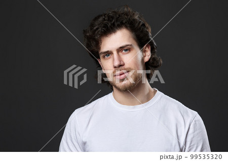 portrait of calm young man on dark gray background 99535320