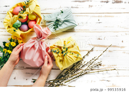 Wrapping a gift in eco friendly reusable fabric package 99535916