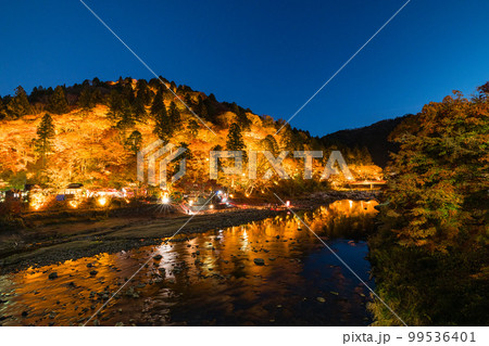 日本　愛知県豊田市足助町　ライトアップされた香嵐渓の飯盛山の紅葉と巴川の夜景 99536401