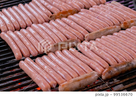 Process of grilling fresh meat sausages on big round grill 99536670