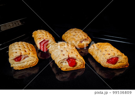 Five baked homemade buns with red strawberry jam in electric oven 99536809
