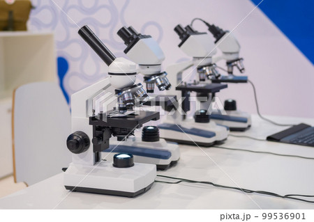 Microscopes on white table at science exhibition - laboratory equipment Microscopes on white table at science exhibition - laboratory equipment 99536901