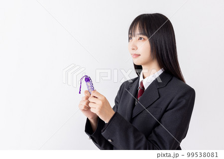 お守りを持ちながら合格発表の掲示板を確認する若い女性 99538081