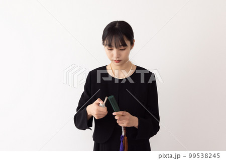 お線香に火を付ける女性 99538245