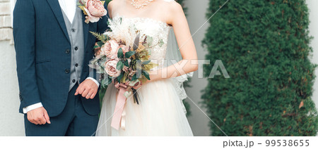 結婚式で結婚式場の庭でブーケを持つ新郎新婦(ガーデンウェディング) 結婚式で結婚式場の庭でブーケを持つ新郎新婦(ガーデンウェディング) 99538655