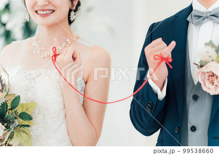 結婚式場で赤い糸で結ばれる新郎新婦（ブライダル・ウェディング） 99538660