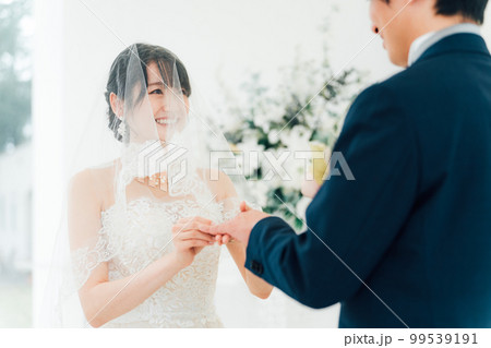 結婚式場で指輪交換する新郎新婦（結婚指輪・マリッジリング・・ウェディング・ブライダル） 99539191