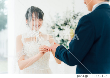 結婚式場で指輪交換する新郎新婦（結婚指輪・マリッジリング・・ウェディング・ブライダル） 99539192