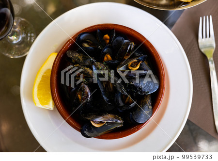Closeup of deliciously appetizing steamed mussel with lemon on clay plate 99539733