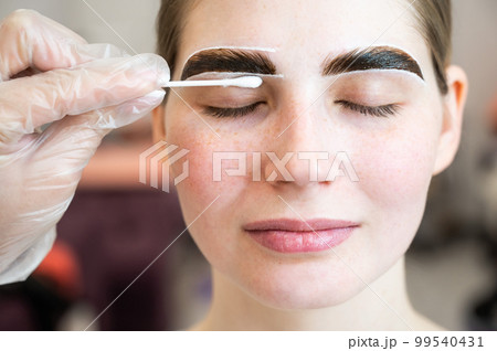 The master paints the eyebrows of a woman. 99540431