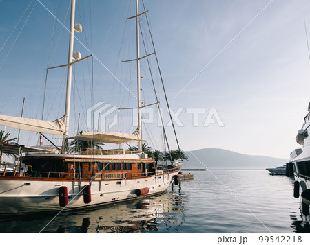 Sailing yacht at the pier with palm trees against the backdrop of mountains Sailing yacht at the pier with palm trees against the backdrop of mountains 99542218