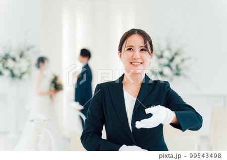 結婚式場・ホテルで腕時計を見るウェディングプランナー・介添人・アテンダー・ホテリエの女性 結婚式場・ホテルで腕時計を見るウェディングプランナー・介添人・アテンダー・ホテリエの女性 99543498