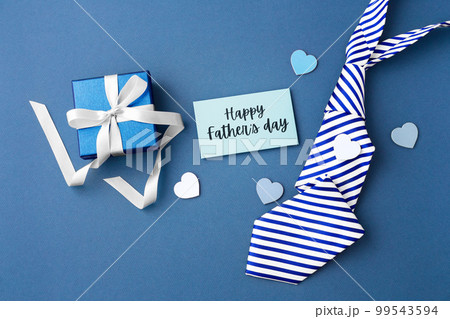 Gift box with happy fathers day card and tie on blue background, top view Gift box with happy fathers day card and tie on blue background, top view 99543594