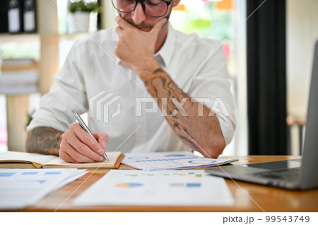 Cropped image of a thoughtful Caucasian businessman working on financial data report 99543749