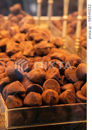 Chocolate truffles bites covered with cocoa a lot on shop window. Heap of chocolate truffle. Vertical photo 99545032
