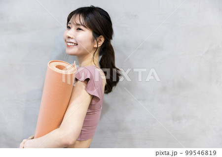 ヨガマットを持って立つ若い女性　ヨガイメージ 99546819