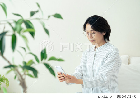 メガネをかけてスマホを見るミドル女性 メガネをかけてスマホを見るミドル女性 99547140