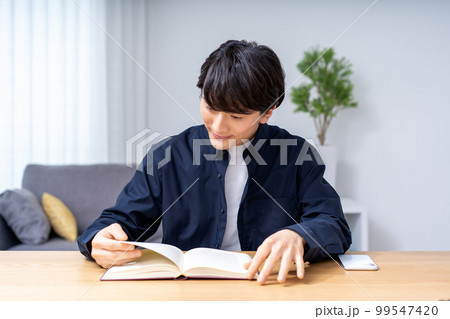 リビングで読書をする若い男性 99547420