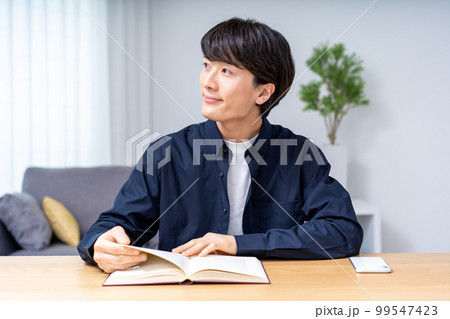 リビングで読書をする若い男性 99547423