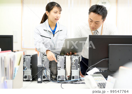 PCの接続を中堅社員に説明する作業服のスタッフ ビジネスイメージ PCの接続を中堅社員に説明する作業服のスタッフ ビジネスイメージ 99547764