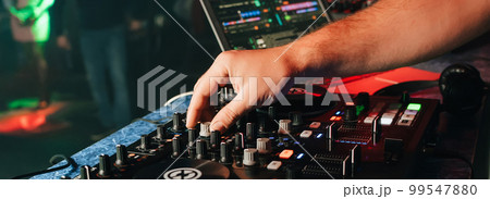hands of a DJ in a booth playing on the mixer 99547880