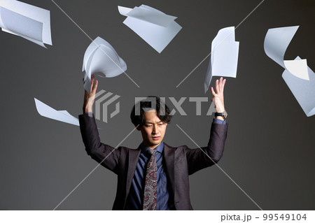 深刻な表情で書類を放り投げる若い男性　多忙　残業　放棄　ビジネスイメージ 99549104