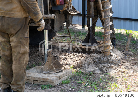 Team of workers with drilling rig on car are drilling artesian well for water in ground. Insertion of metal casing pipe into ground, installation of individual drinking supply, June 28, 2022, Russia, 99549130