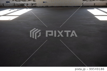 The leveled rough floor in a house under construction with a semi-dry cement screed is a smooth surface with light from the windows 99549186
