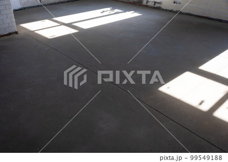 The leveled rough floor in a house under construction with a semi-dry cement screed is a smooth surface with light from the windows 99549188