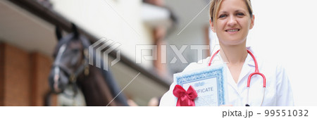 Beautiful woman veterinarian is holding medical certificate next to horse 99551032