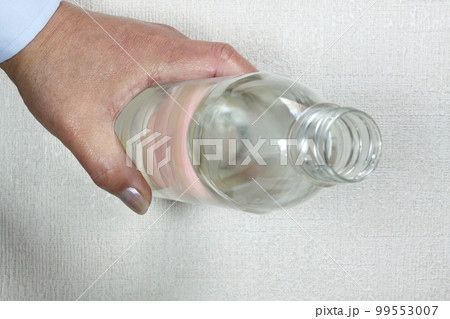 水が入ったペットボトルを持つ男性の手元 99553007