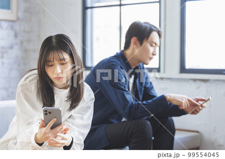 スマホを操作する男女 スマホを操作する男女 99554045