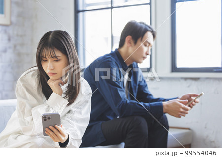 スマホを操作する男女 99554046