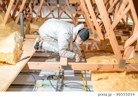 a worker in protective overalls works with glass wool 99555054
