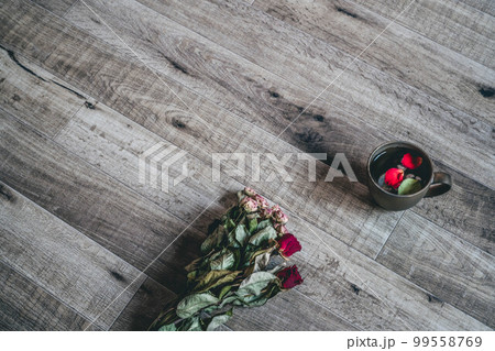 木目の背景と花びらが入ったコーヒーカップ 99558769