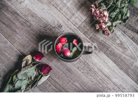 木目の背景と花びらが入ったコーヒーカップ 99558793