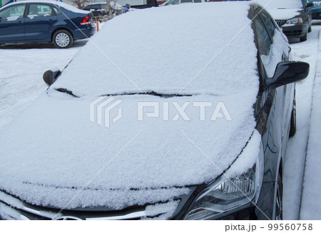 The parked car is on the road, covered with snow 99560758