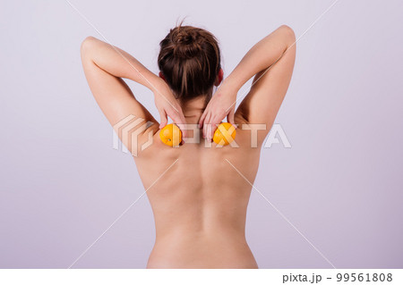 Slender athletic woman topless holds a tangerine in her hands. Cellulite. Healthy lifestyle Slender athletic woman topless holds a tangerine in her hands. Cellulite. Healthy lifestyle 99561808