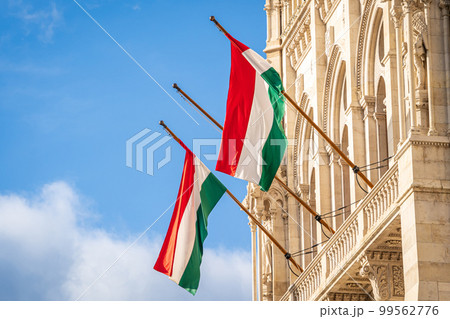 Hungary National flags. Two Hungarian flags on flagpole hanging on a building against the blue sky. Hungary National flags. Two Hungarian flags on flagpole hanging on a building against the blue sky. 99562776