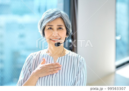 オフィスでヘッドセットをつけて対応するベテラン女性オペレーター 99563307