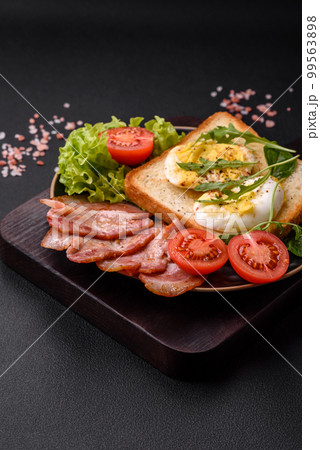 Delicious healthy lunch consisting of bacon, toast, eggs and tomatoes 99563898