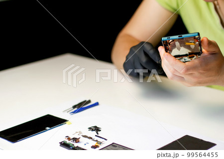 Repairman. Defocus technician repairing the smartphone's motherboard in the lab. Mobile phone, electronic, repairing, upgrade and technology. Broken smartphone. Design 99564455