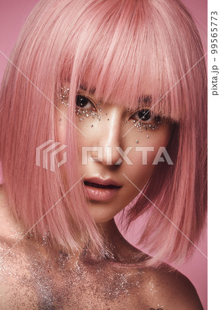 Beautiful woman in a pink wig and creative makeup with rhinestones. Beauty face. Beautiful woman in a pink wig and creative makeup with rhinestones. Beauty face. 99565773