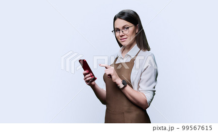 Young smiling woman in apron with smartphone, on white background 99567615