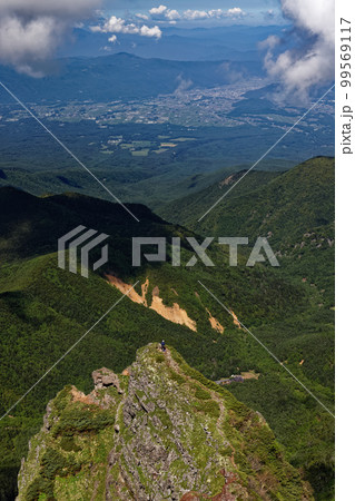 八ヶ岳連峰・横岳山頂から大同心のクライマーと茅野方面の町並みを望む 99569117